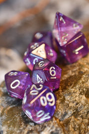 A set of translucent purple polyhedral gaming dice with white numbers, arranged on a textured brown rock surface.