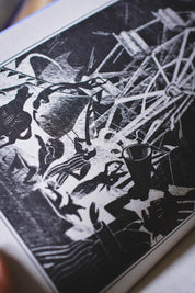 A close-up of a black and white linocut or woodcut print depicting a circus scene with animals and a ringmaster, photographed at an angle.