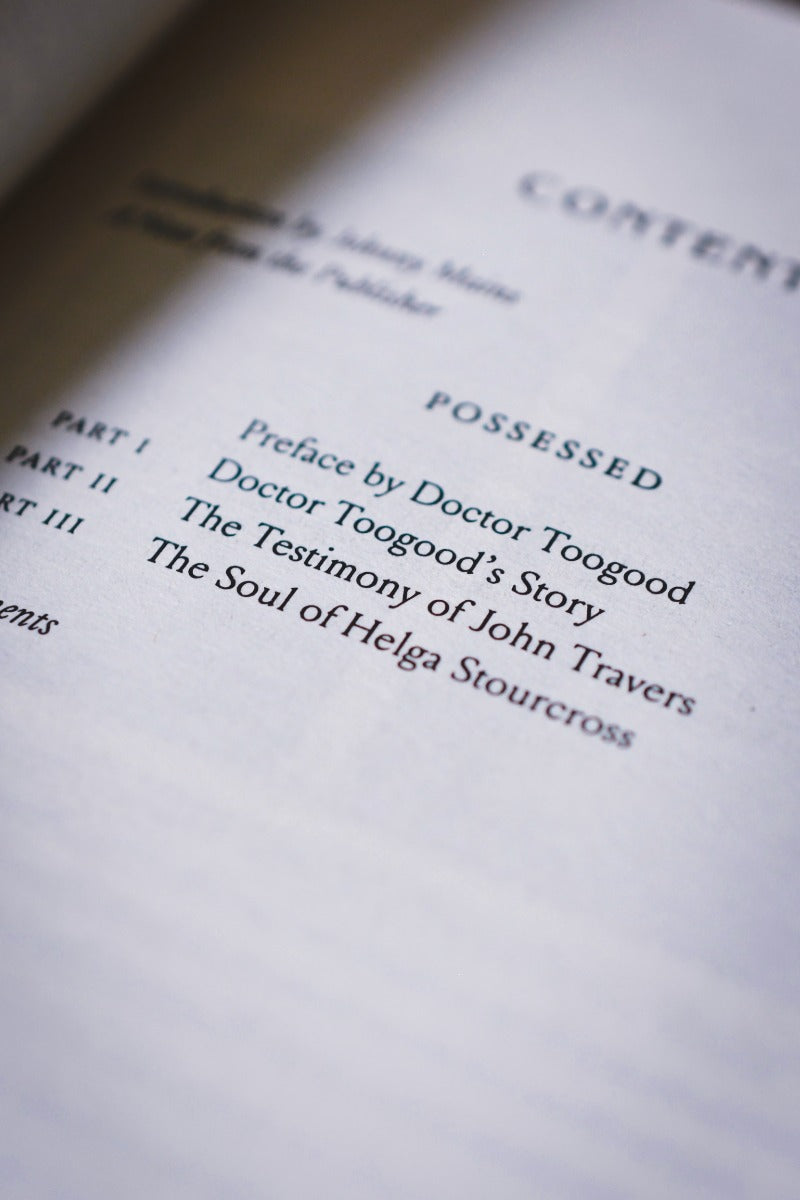 A close-up, angled view of a book's table of contents page, showing the title 'POSSESSED' and chapter titles printed in black on off-white paper.