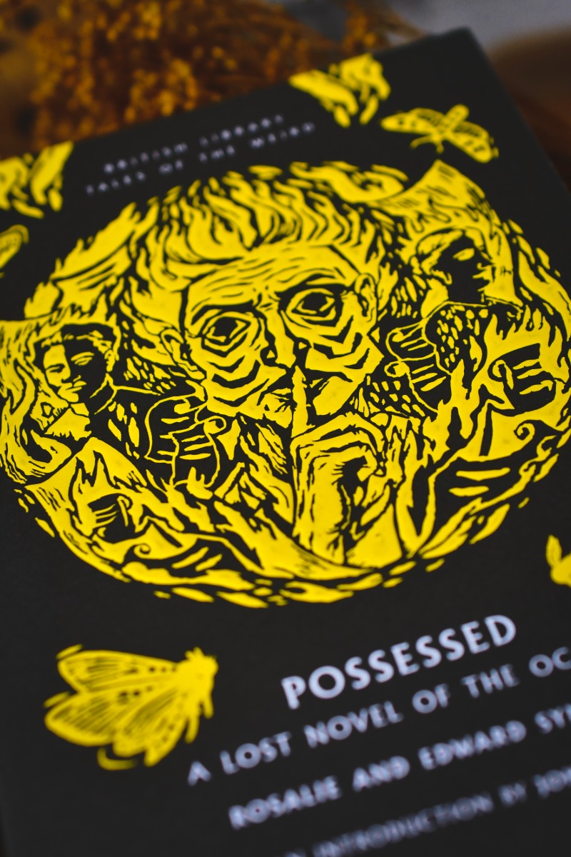 A close-up of a book cover for 'Possessed: A Lost Novel of the Oakham Forest' by Rosalie and Edward Styron, featuring a bold yellow graphic illustration on a black background.